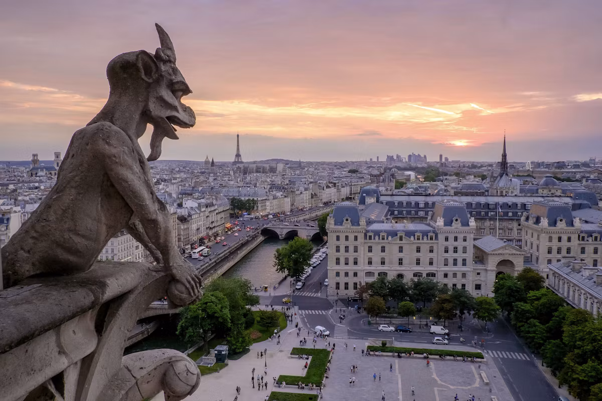 A Notre-Dame chimera looking over the Seine towards the Eiffel Tower at dusk
