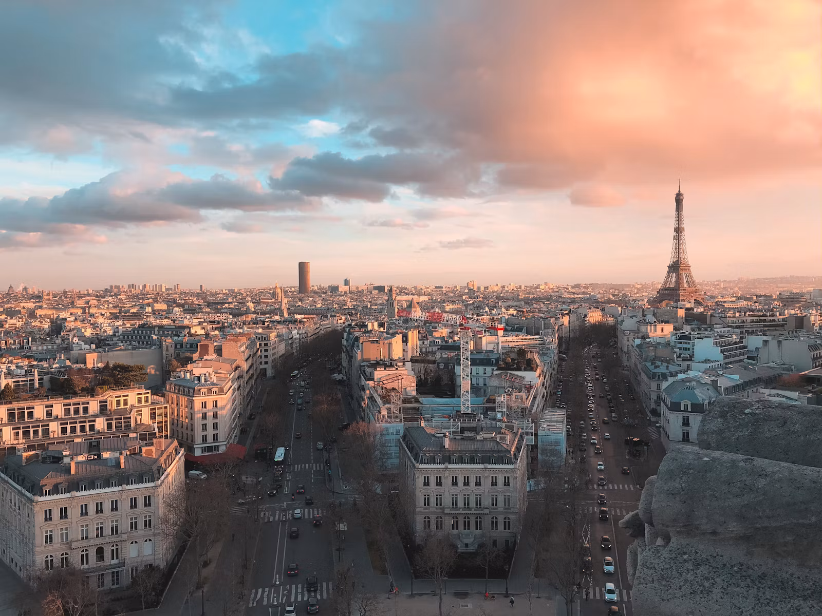 Paris rooftops and avenues from the Arc de Triomphe, with the Eiffel Tower in daylight