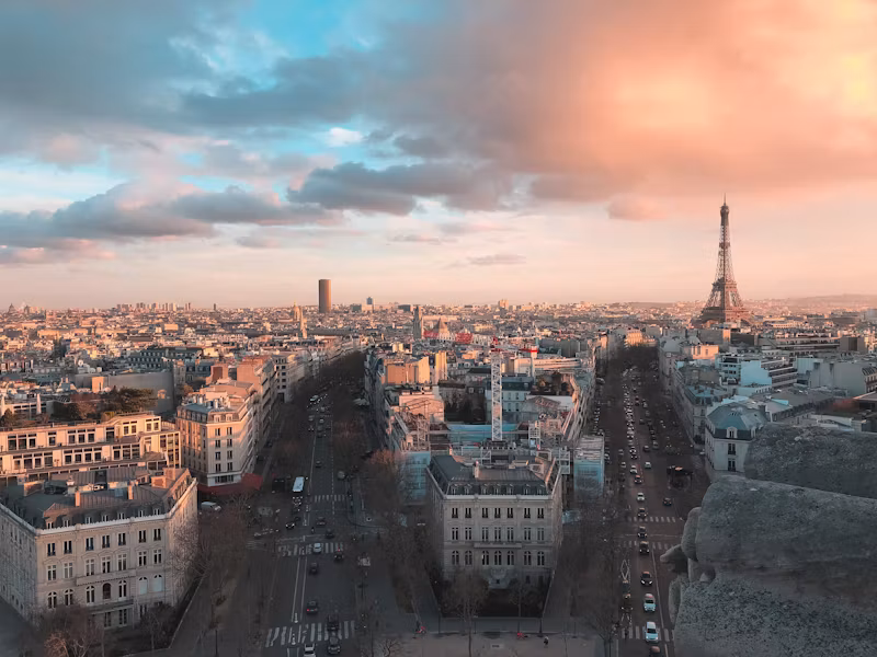 Paris rooftops and avenues from the Arc de Triomphe, with the Eiffel Tower in daylight