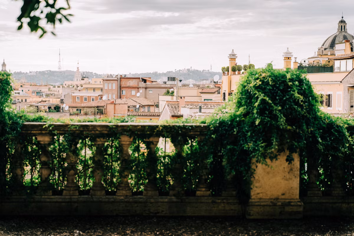 Rome's rooftops seen over an ivy-covered garden balustrade