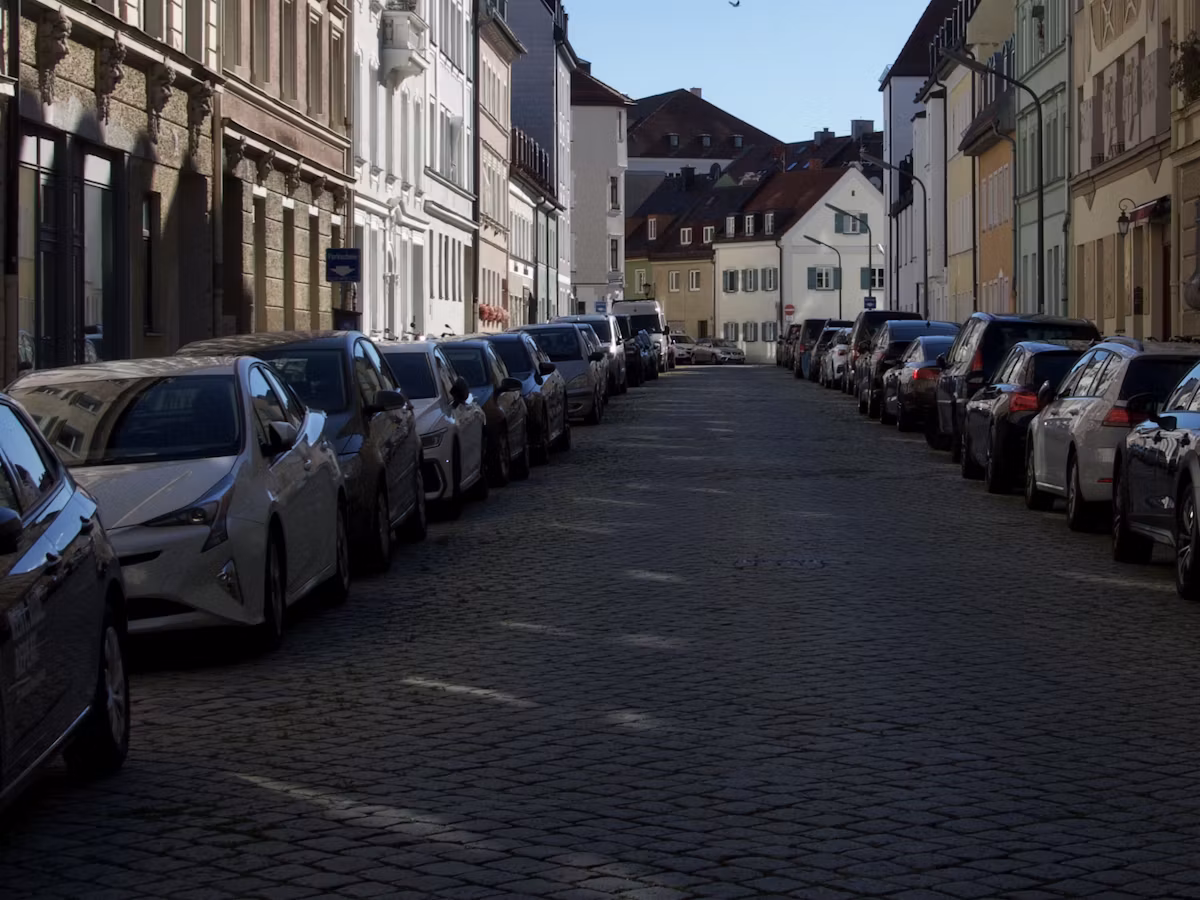 Both kerbs of a cobbled Munich side street filled with parked cars